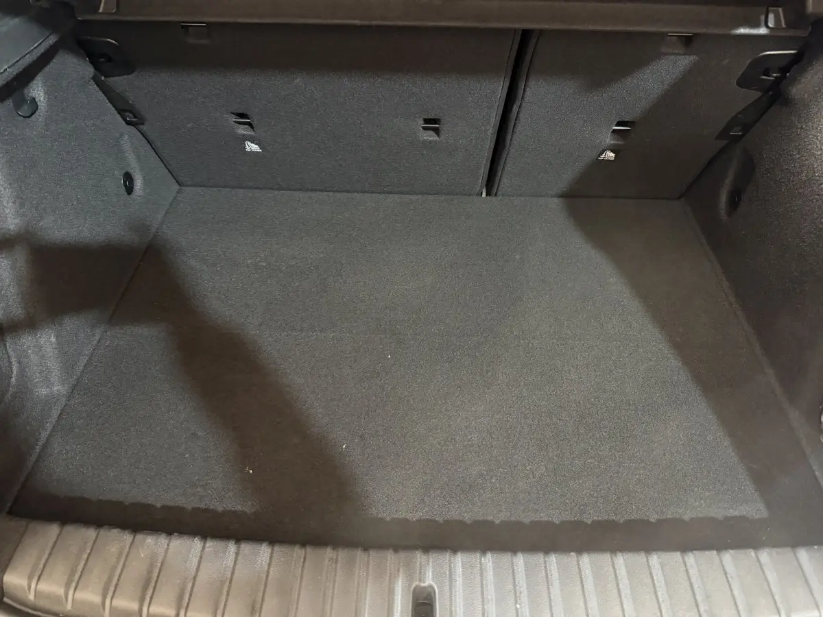 Coffre vide vu de face de la BMW Série 1 116i Business Design 2023, revêtement noir et banquette rabattable.