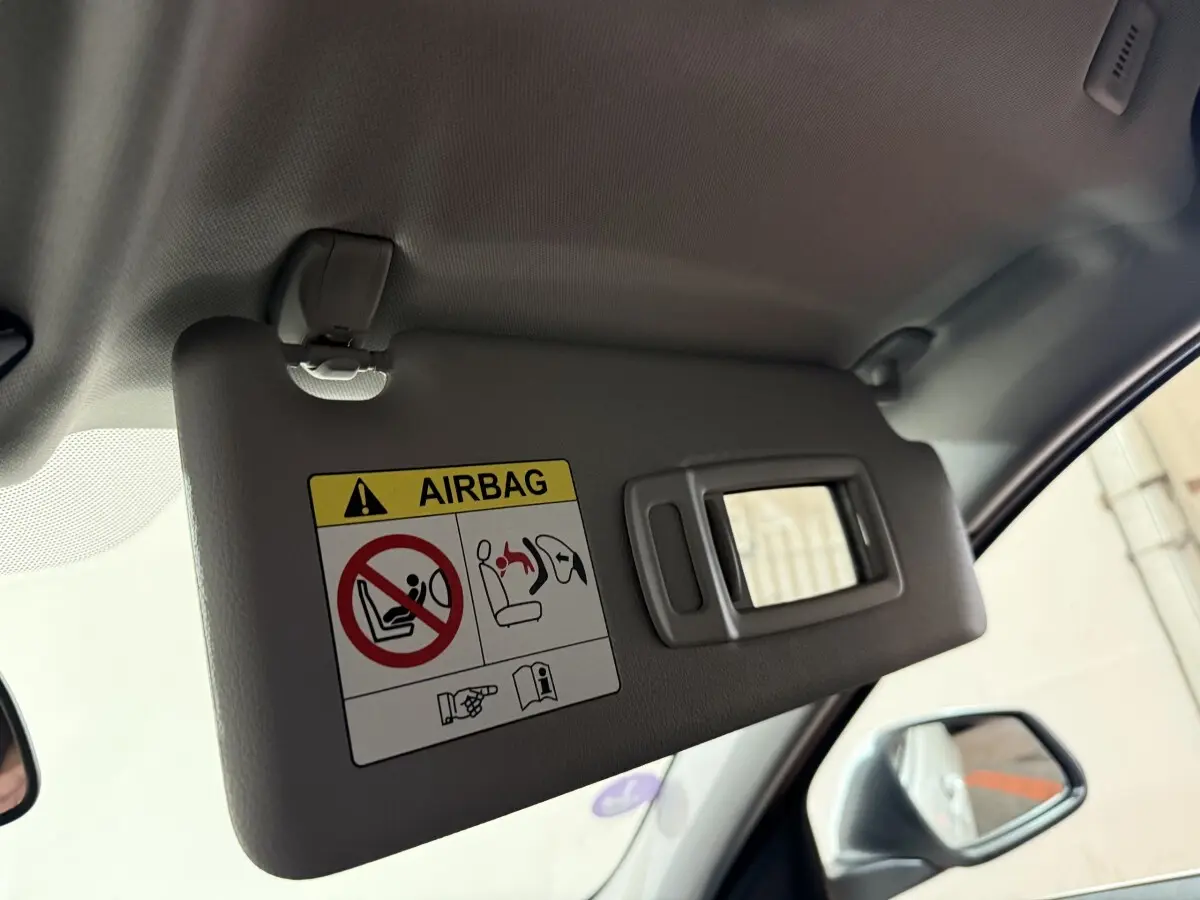 Détail du pare-soleil côté conducteur avec miroir et avertissement airbag dans une BMW Série 1 blanche 2023.