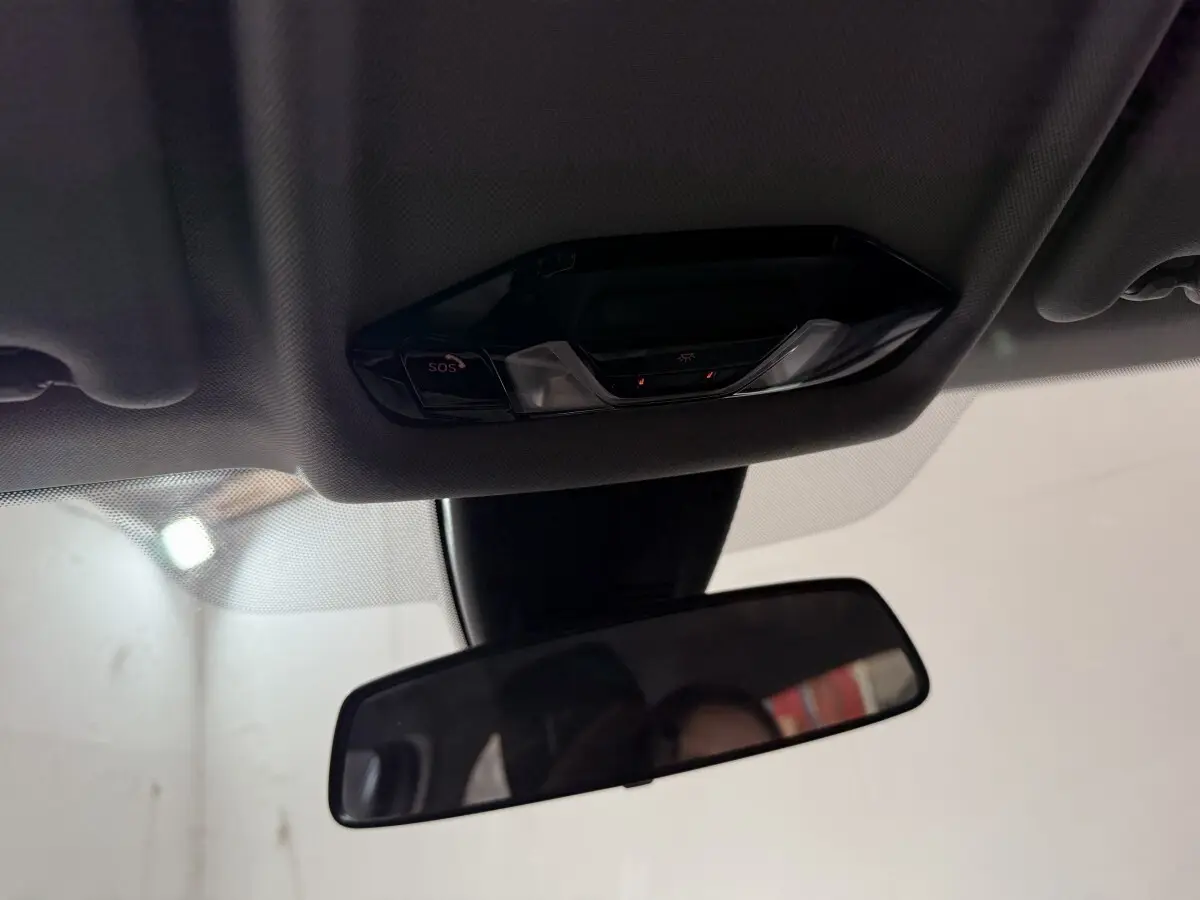 Vue intérieure rapprochée du plafonnier et du rétroviseur intérieur d'une BMW Série 1 blanche de 2023.
