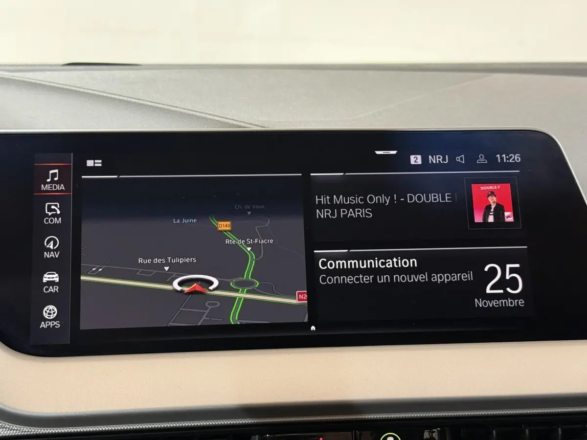 Écran tactile central de la BMW Série 1 116i blanc, affichant navigation et communication, intérieur beige.