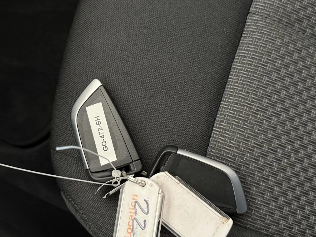 Gros plan sur une clé BMW noire et argent posée sur un siège tissu gris foncé à motifs.