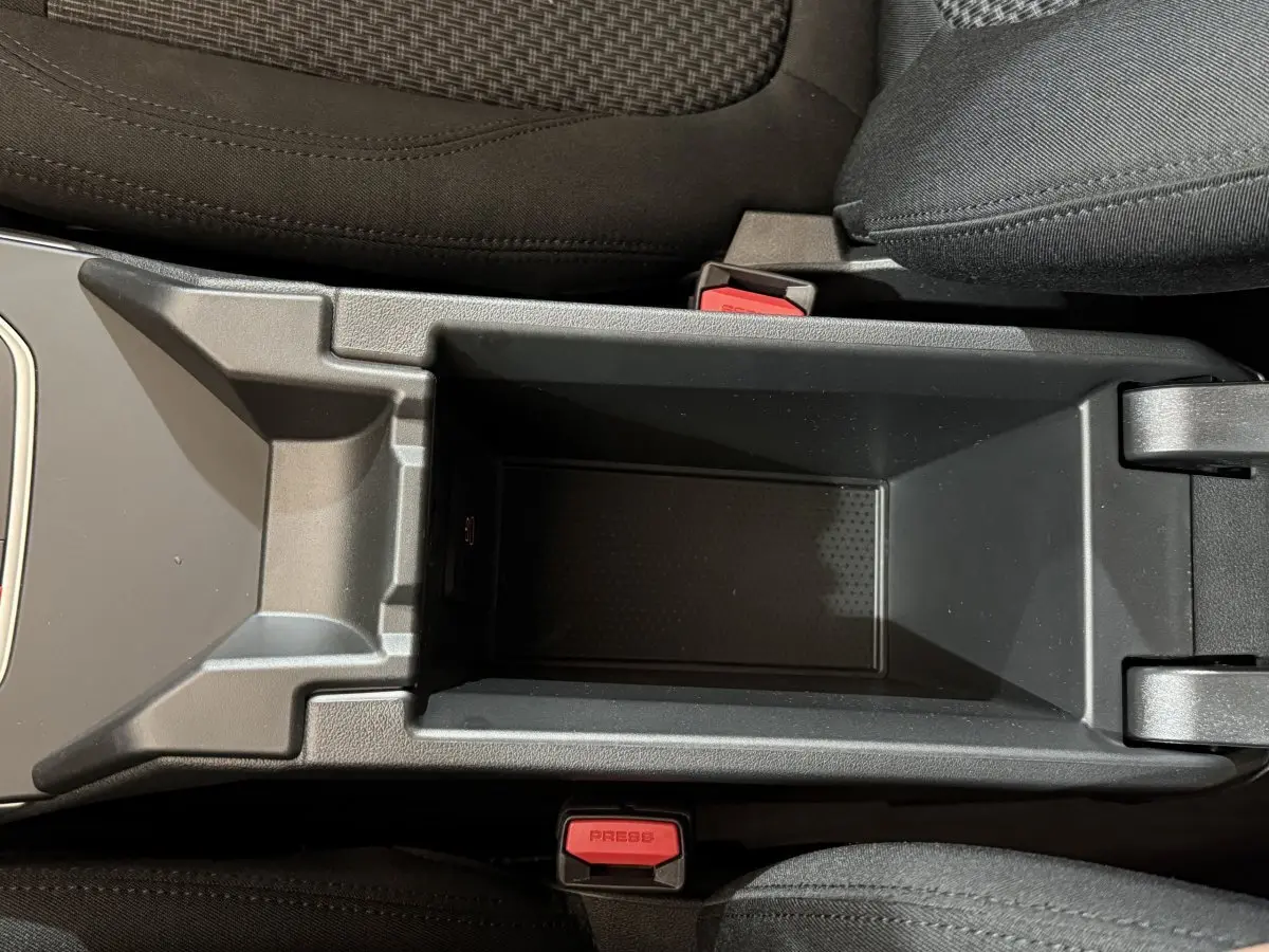 Vue plongeante sur le rangement central noir entre les sièges avant d'une BMW Série 1 116i Business Design 2023.