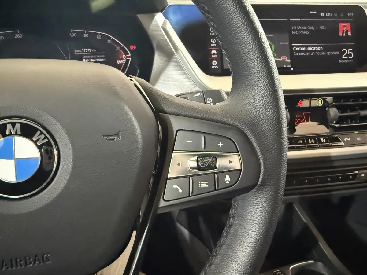 Vue rapprochée du volant cuir multifonctions et du tableau de bord numérique de la BMW Série 1 blanche 2023.