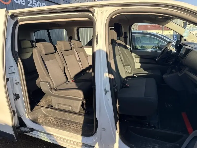 Vue latérale intérieure du Citroën Jumpy XL blanc, montrant les sièges tissu Mica et la porte coulissante ouverte.