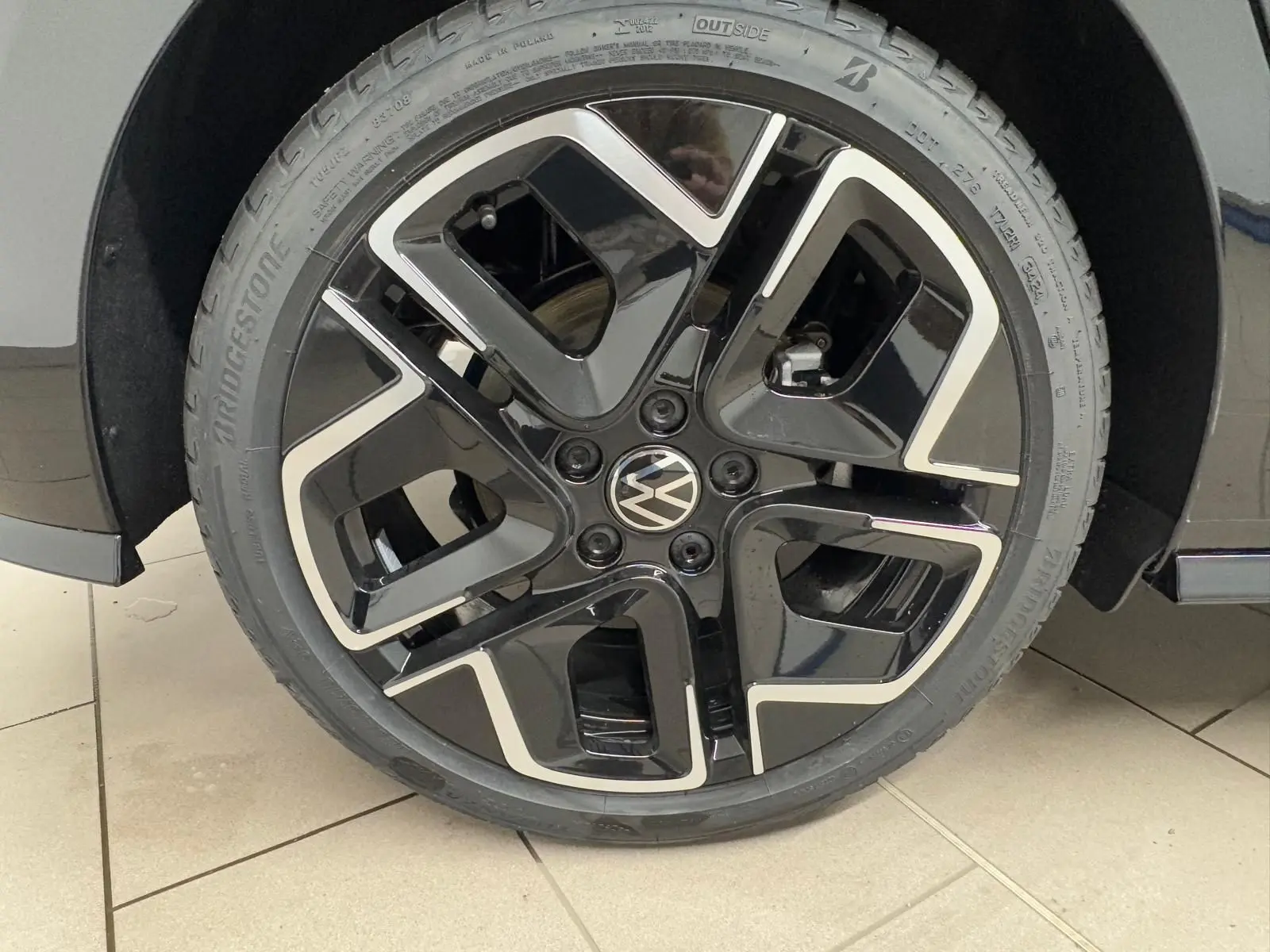 Gros plan sur la roue avant droite noire et argentée d'une Volkswagen Golf 2.0 TDI 150 DSG7 R-Line.