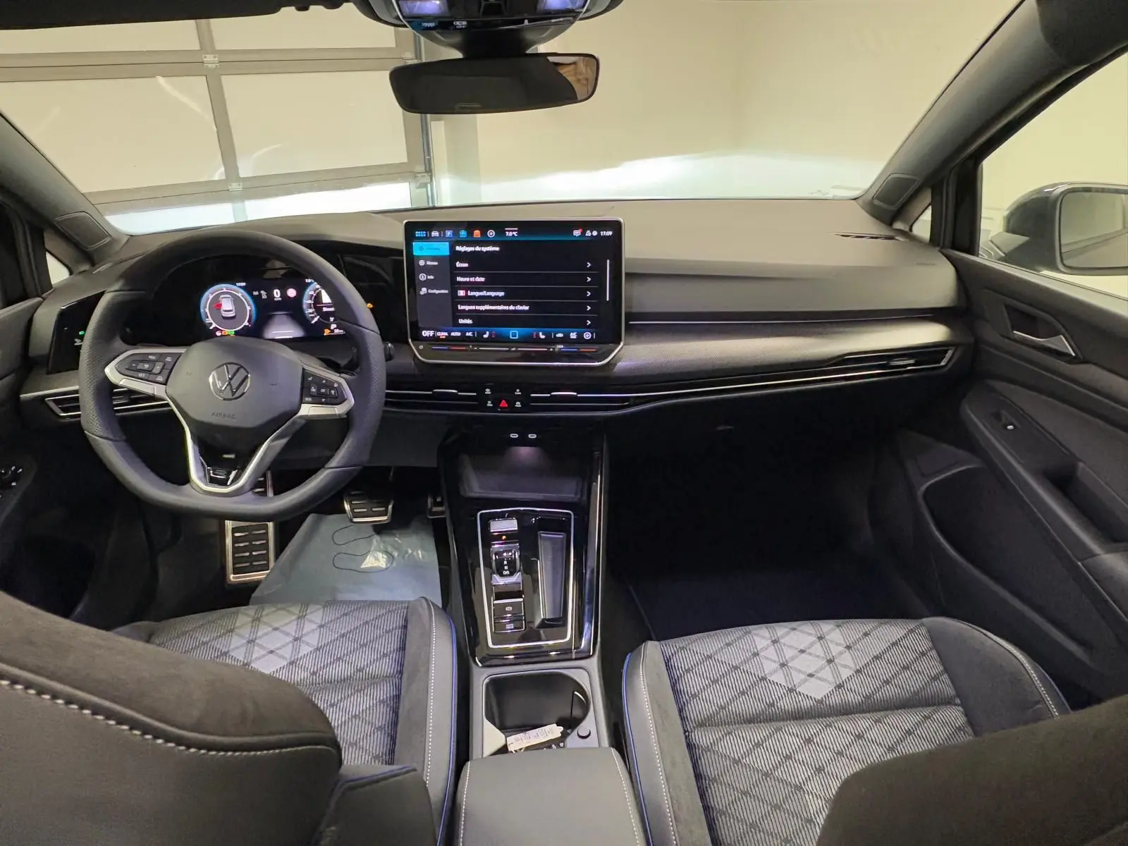 Vue intérieure avant de la Volkswagen Golf 2.0 TDI 150 DSG7 R-Line avec tableau de bord moderne et sièges tissu noir.