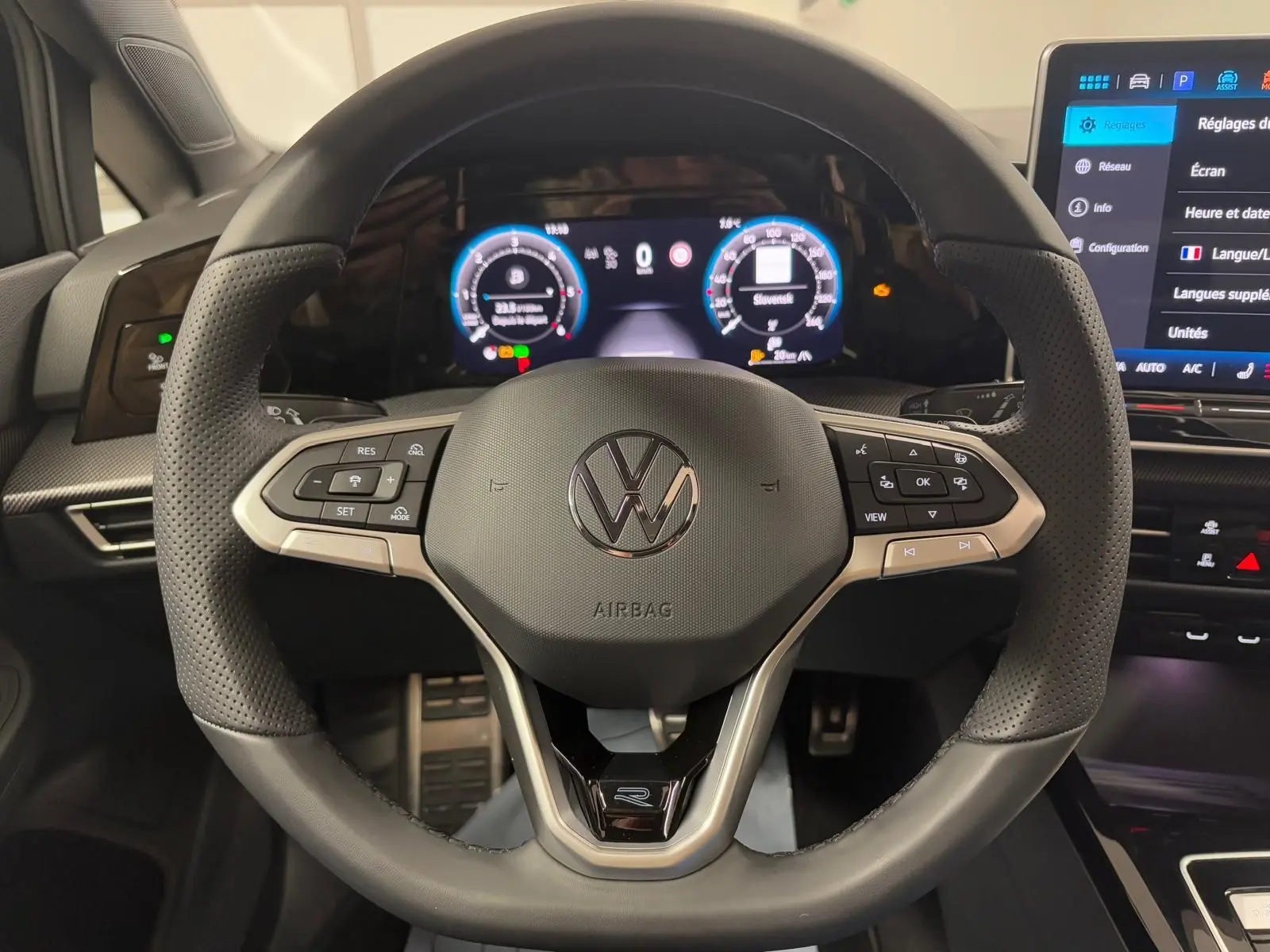 Vue rapprochée du volant cuir noir perforé d'une Volkswagen Golf 2.0 TDI 150 DSG7 R-Line avec tableau de bord digital.