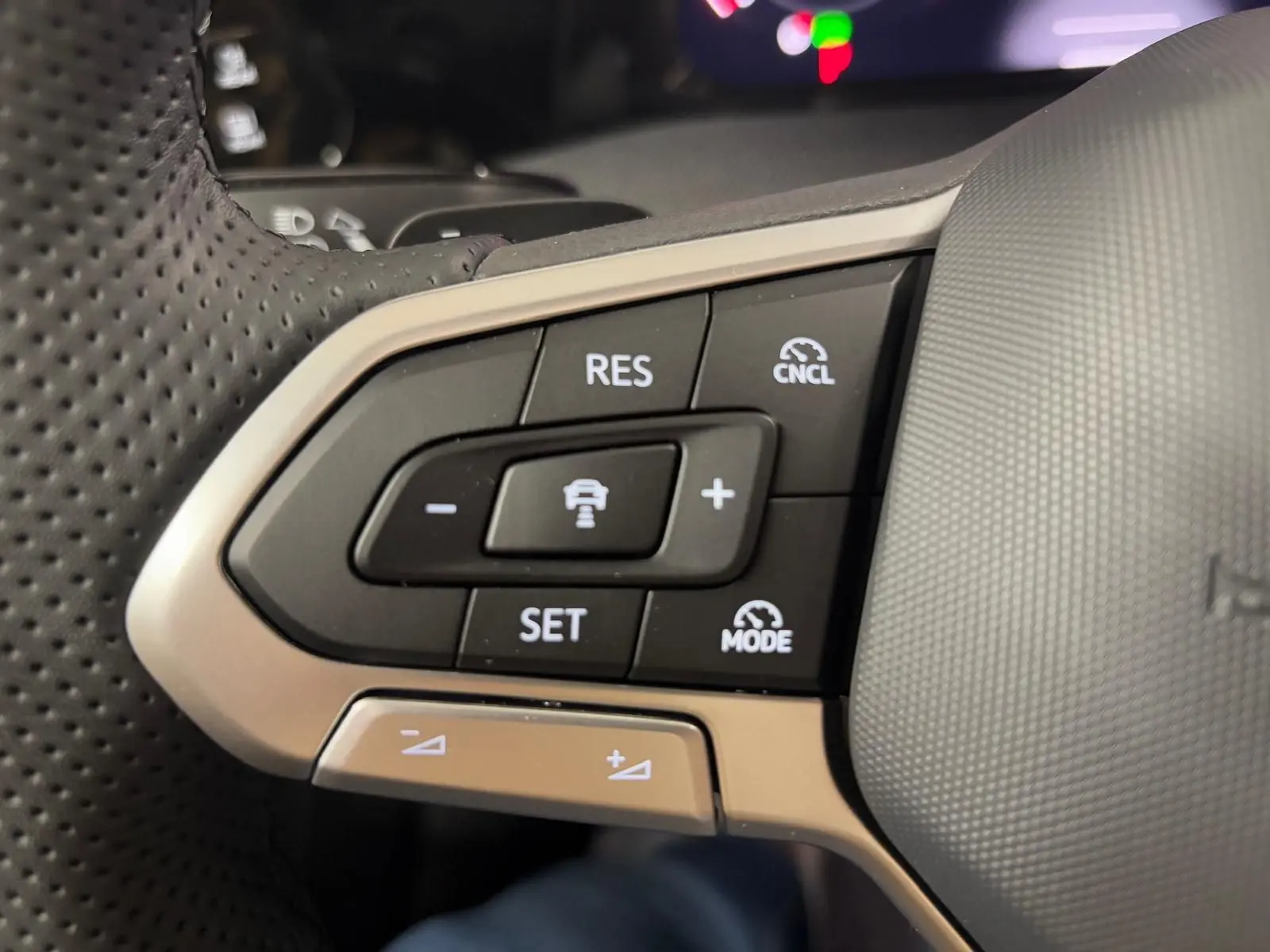 Gros plan sur les commandes de régulateur de vitesse au volant cuir perforé de la Volkswagen Golf 2.0 TDI noir grenadille.