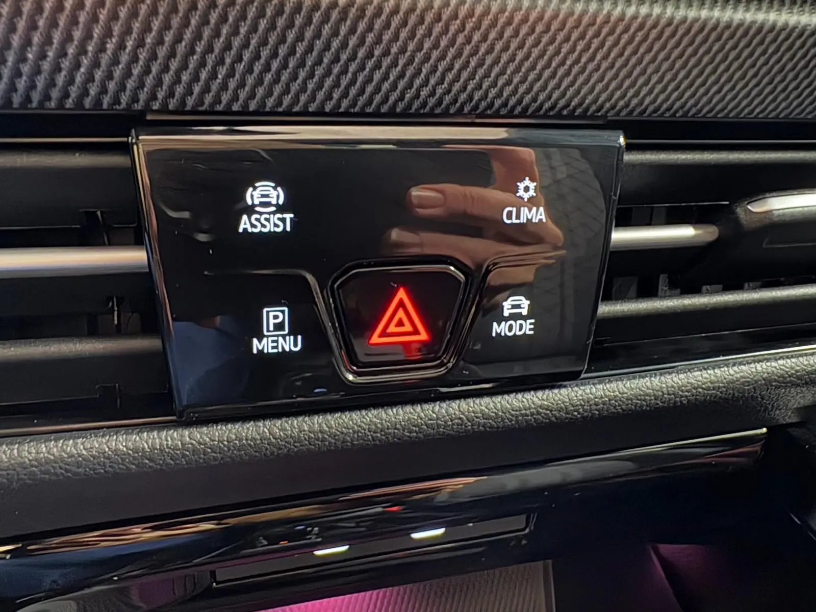 Gros plan sur la console centrale noire brillante de la Volkswagen Golf 2.0 TDI, avec boutons d’alerte et assistances visibles.