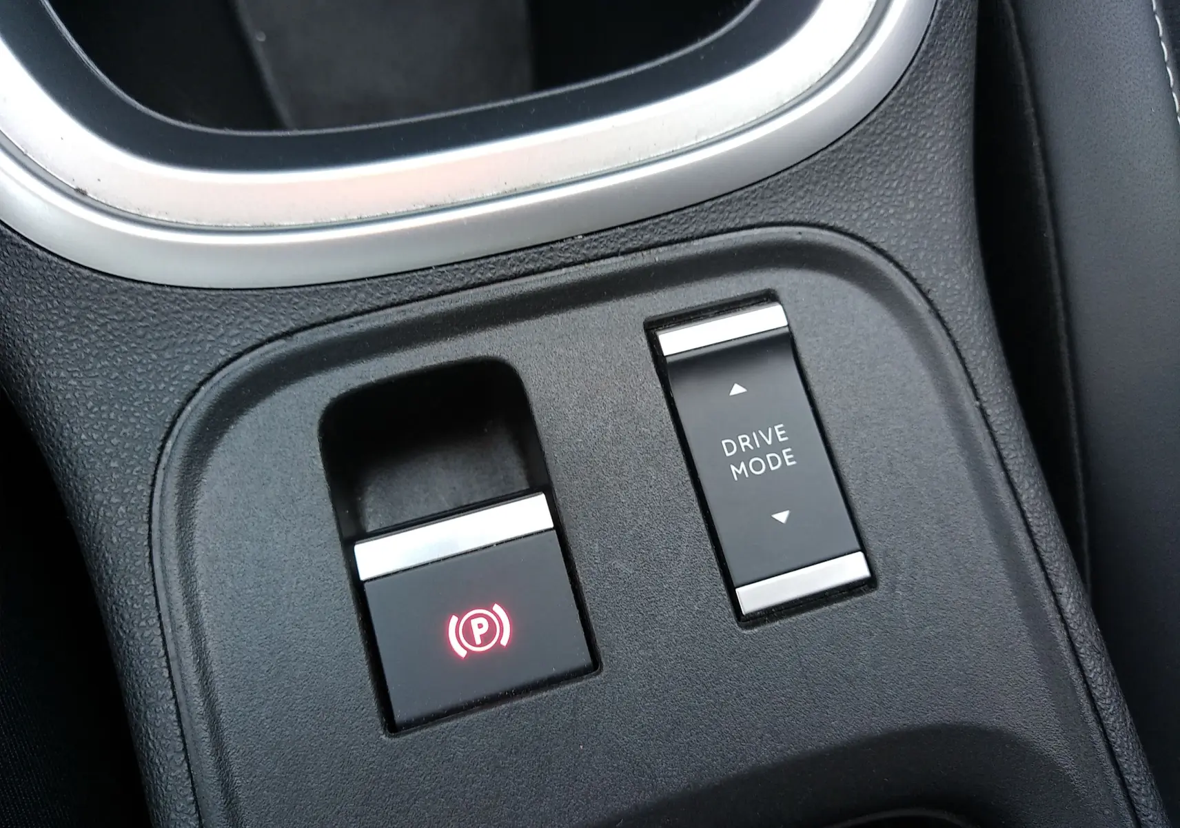 Gros plan sur la console centrale noire du Jeep Avenger eHYBRID avec bouton frein à main électronique et sélection mode de conduite.