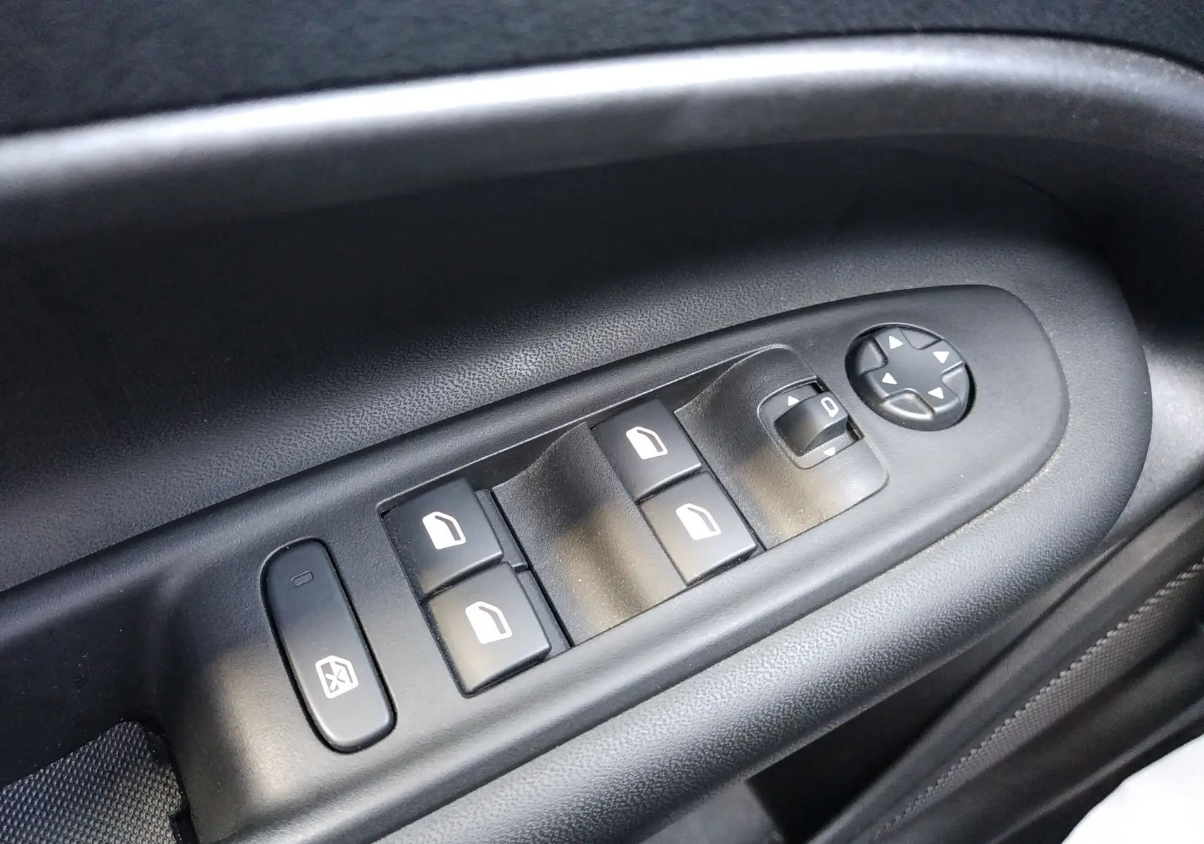 Détail des commandes de lève-vitres et réglage des rétroviseurs sur la porte côté gauche d'un Jeep Avenger gris.