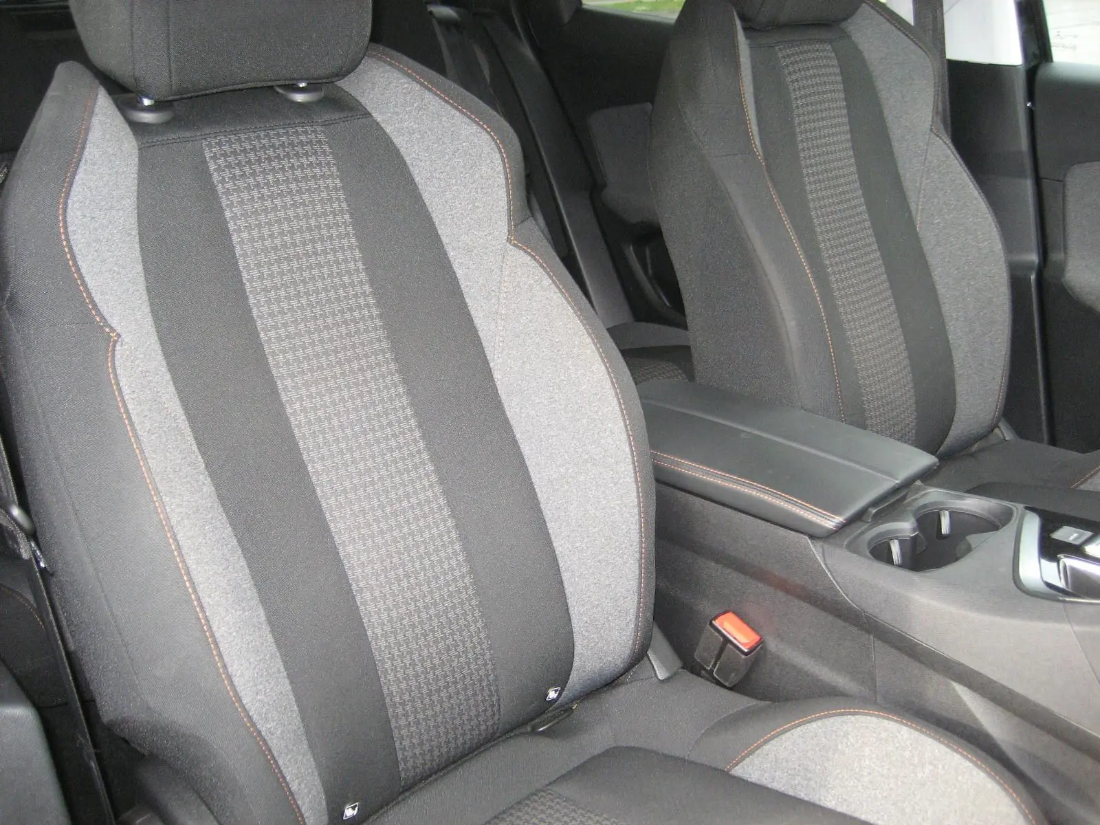Gros plan sur les sièges avant gris et noirs du Peugeot 3008 Business 2020 avec surpiqûres orange et console centrale visible.