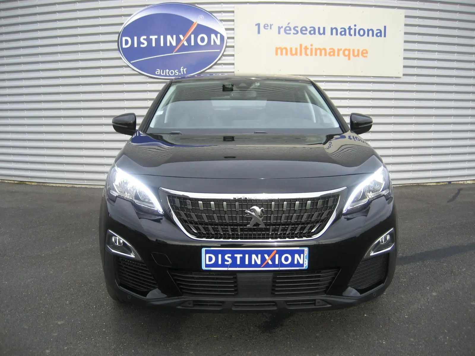 Peugeot 3008 Business noir vue de face avec calandre chromée et phares LED allumés sur parking.