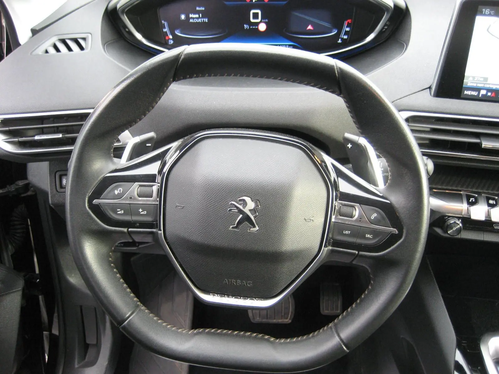 Volant cuir noir avec commandes intégrées et logo Peugeot visible, tableau de bord numérique en arrière-plan du Peugeot 3008 Business 2020.