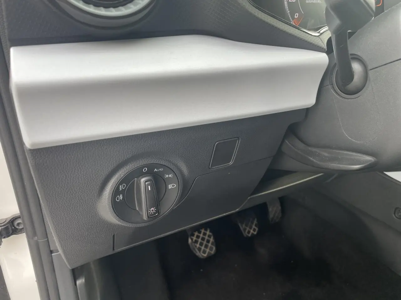 Détail du tableau de bord côté gauche de la SEAT Ibiza blanche 2025 avec commande des feux et pédalier manuel visible.