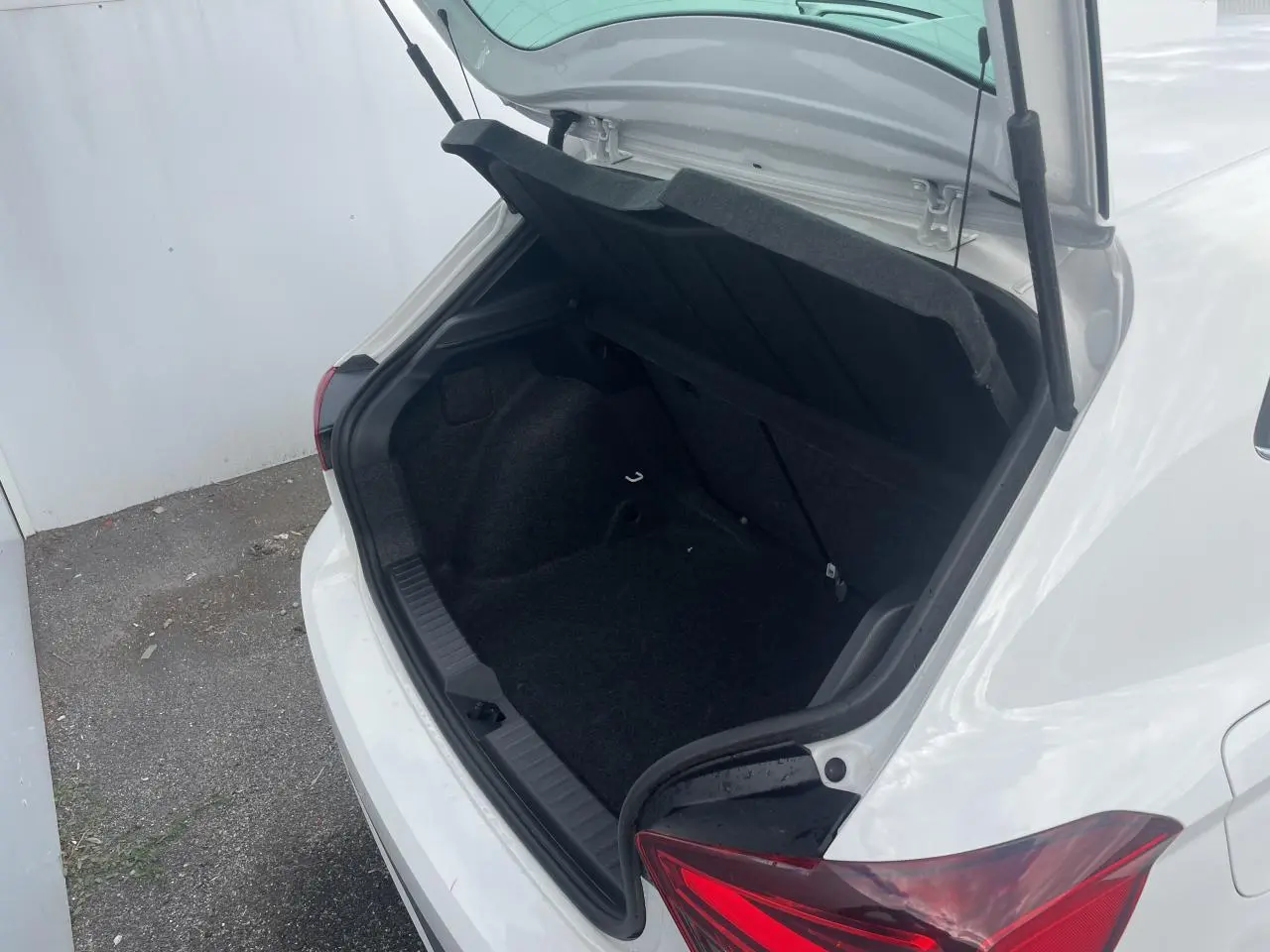 Coffre ouvert vu de l'arrière droit d'une SEAT IBIZA blanche avec feux arrière LED en triangle.
