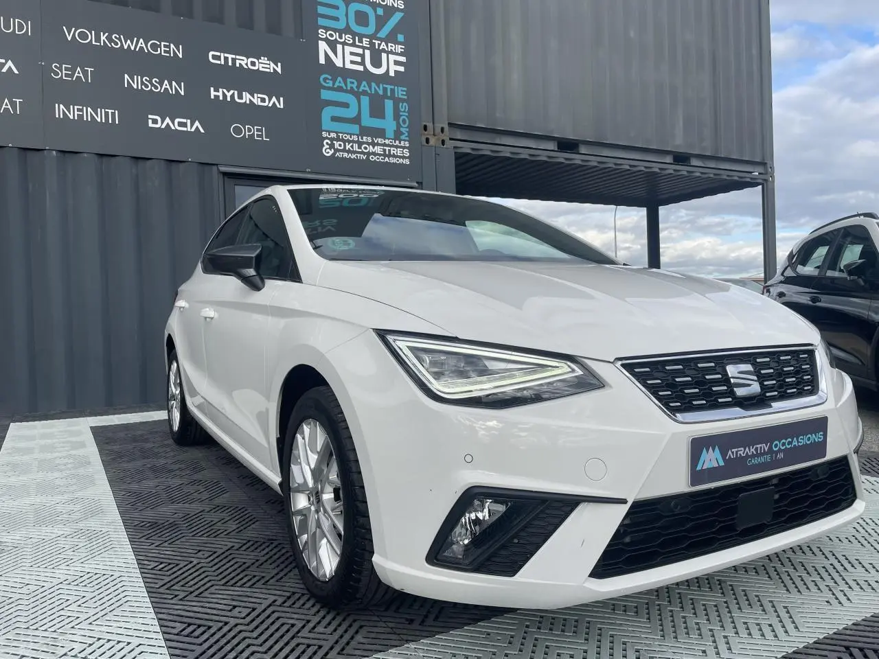 SEAT Ibiza blanche vue en 3/4 avant droit, avec phares LED triangulaires et jantes alliage 16 pouces.