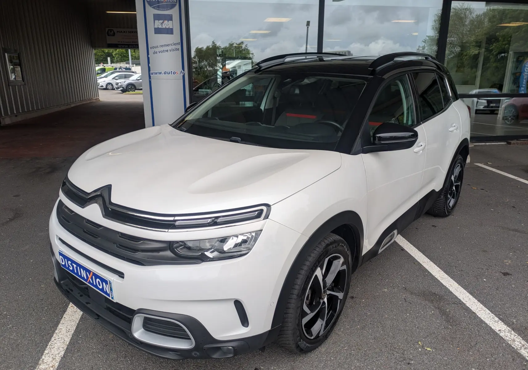 Vue 3/4 avant droite d'un Citroën C5 Aircross blanc avec toit noir, jantes noires et détails chromés.