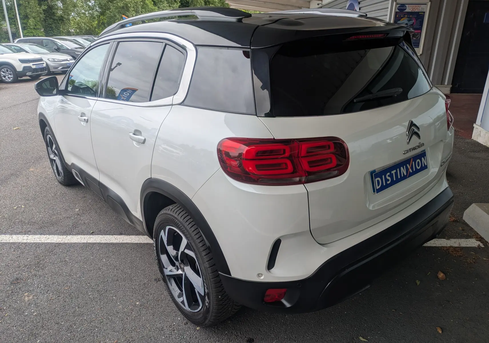 Vue 3/4 arrière droite d'un Citroën C5 Aircross blanc avec toit noir et feux arrière distinctifs en forme de double 8.