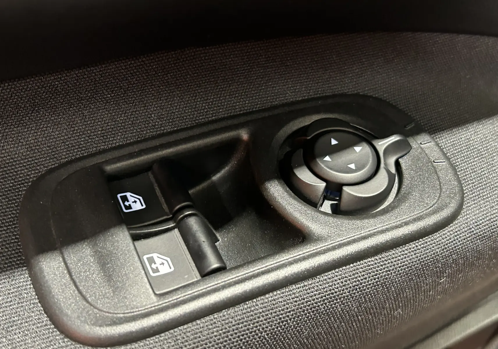 Gros plan sur les commandes noires des vitres électriques et du réglage des rétroviseurs d'une FIAT 500 électrique 2023.
