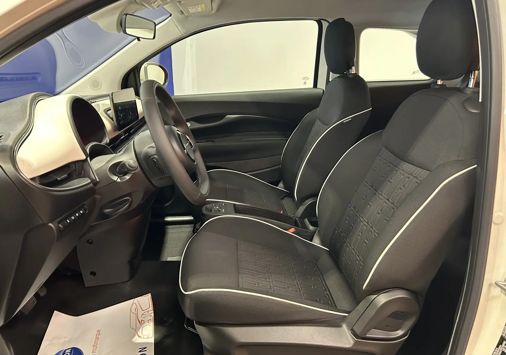 Intérieur de la Fiat 500 électrique 2023 vue côté droit, sièges noirs avec surpiqûres blanches et tableau de bord clair.