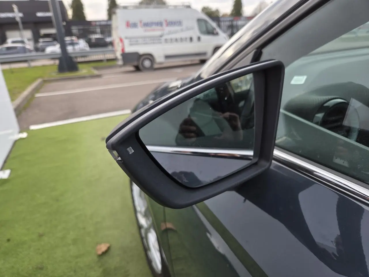 Rétroviseur côté gauche en gros plan sur SEAT Ibiza 2025 bleu Fjord métallisé stationnée sur pelouse artificielle.