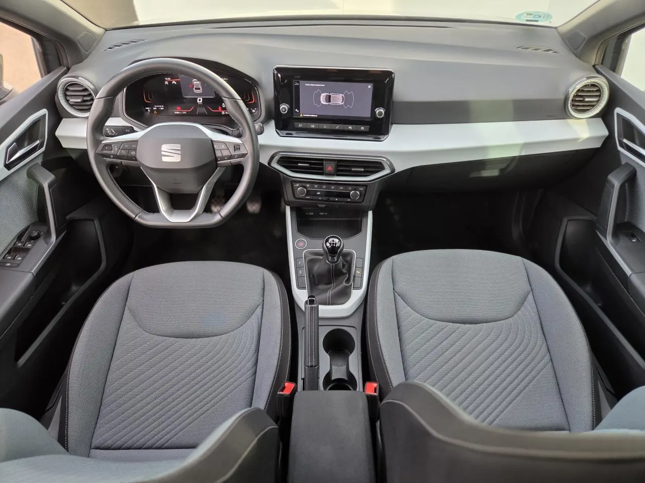 Intérieur de la SEAT Ibiza 2025 vu de face, tableau de bord moderne avec écran tactile et volant multifonction.