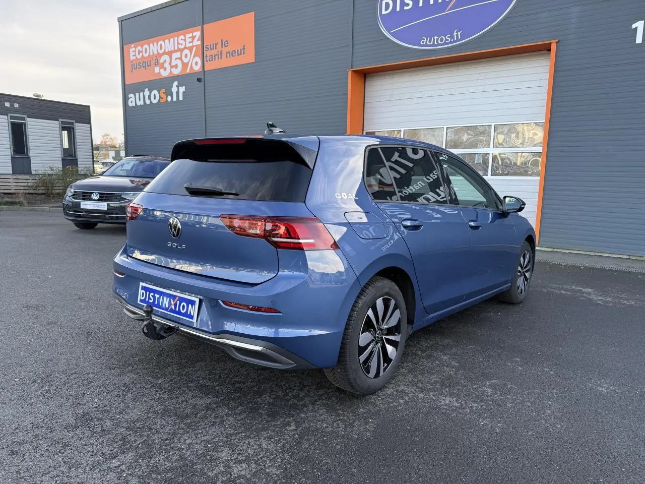 Volkswagen Golf 2025 bleu métallisé en 3/4 arrière droit avec attelage escamotable et vitres arrière surteintées.