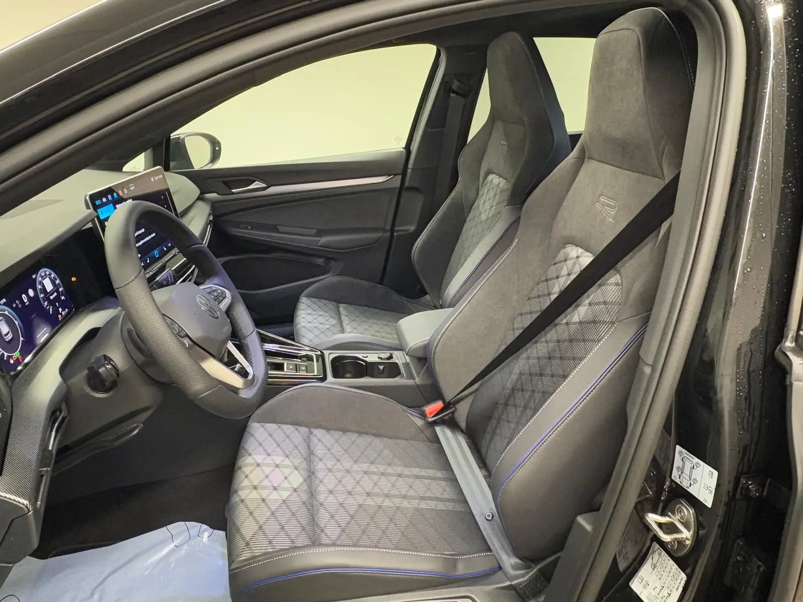 Vue intérieure côté conducteur de la Volkswagen Golf 2.0 TDI R-Line 2026 avec sièges sport gris et volant multifonction.