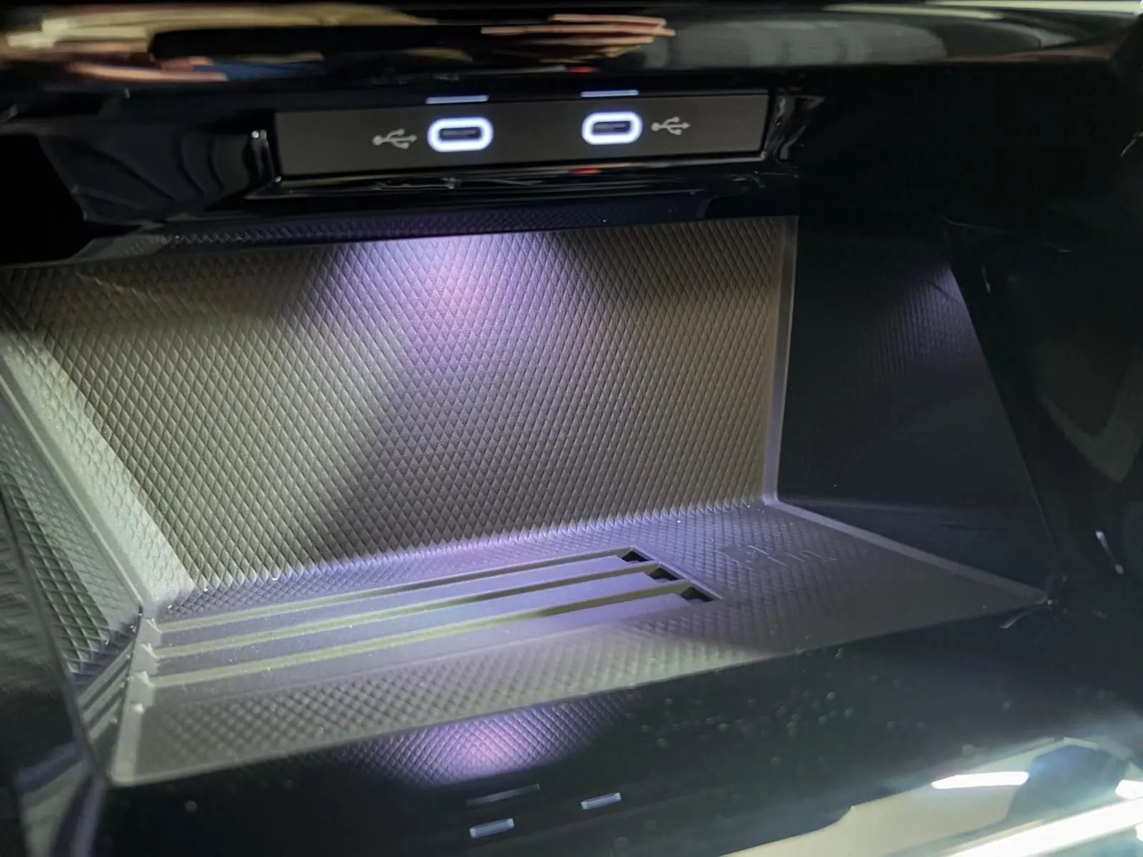 Détail du compartiment de recharge avec ports USB lumineux dans une Volkswagen Golf Noir Grenadille 2026.