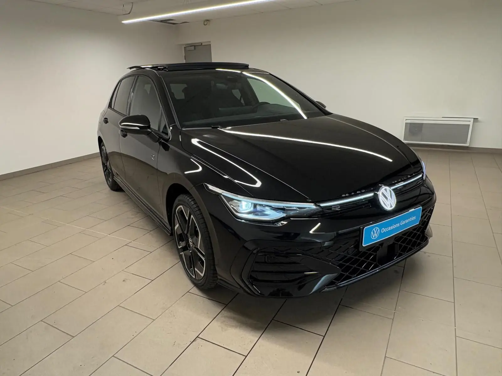 Volkswagen Golf 2.0 TDI R-Line noir grenadille en 3/4 avant droit avec toit ouvrant panoramique ouvert.