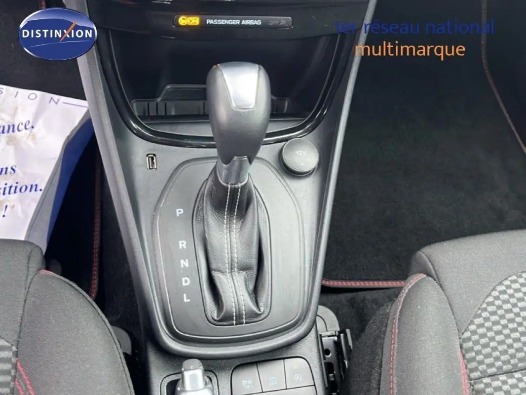 Vue rapprochée de la console centrale du Ford Puma 2024, boîte auto avec levier en cuir et sièges tissu gris foncé.