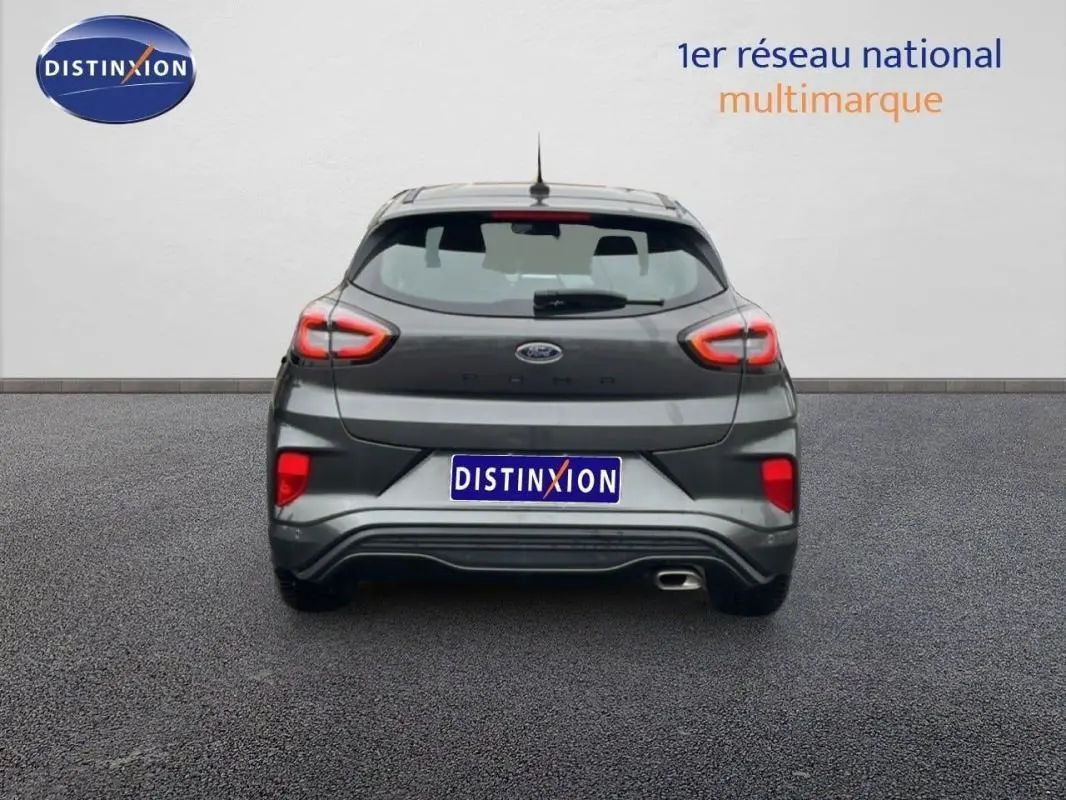Vue arrière d'une Ford Puma gris foncé 2024 avec feux arrière allumés et échappement visible côté droit.
