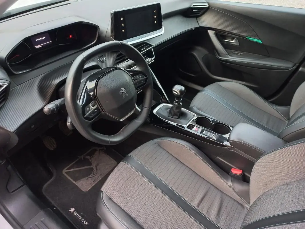 Intérieur avant droit de Peugeot 2008 blanc 2021, volant compact, écran tactile et levier de vitesse manuel visibles.