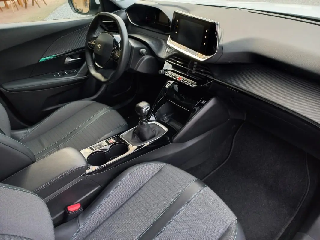 Vue intérieure côté conducteur du Peugeot 2008 blanc de 2021, avec tableau de bord moderne et boîte manuelle.