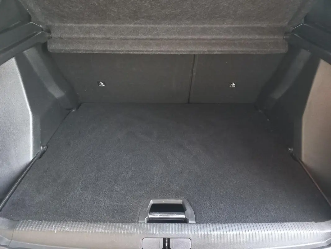Coffre spacieux et propre du Peugeot 2008 blanc, vue intérieure depuis l'arrière avec tapis noir et seuil de chargement visible.