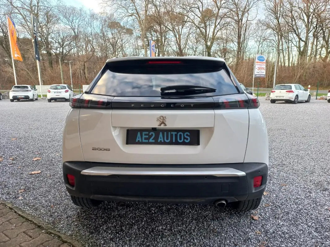 Vue arrière d'un Peugeot 2008 blanc de 2021 avec feux arrière noirs et plaque AE2 AUTOS visible.