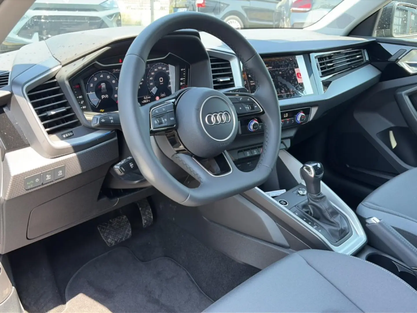 Intérieur de l'Audi A1 Sportback 30 TFSI 2026, vue côté conducteur sur le volant cuir et la console centrale.