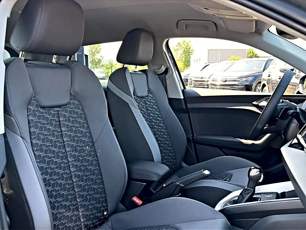 Vue intérieure côté droit de l’Audi A1 Sportback 2026, sièges sport noirs avec motifs géométriques et accoudoir central.