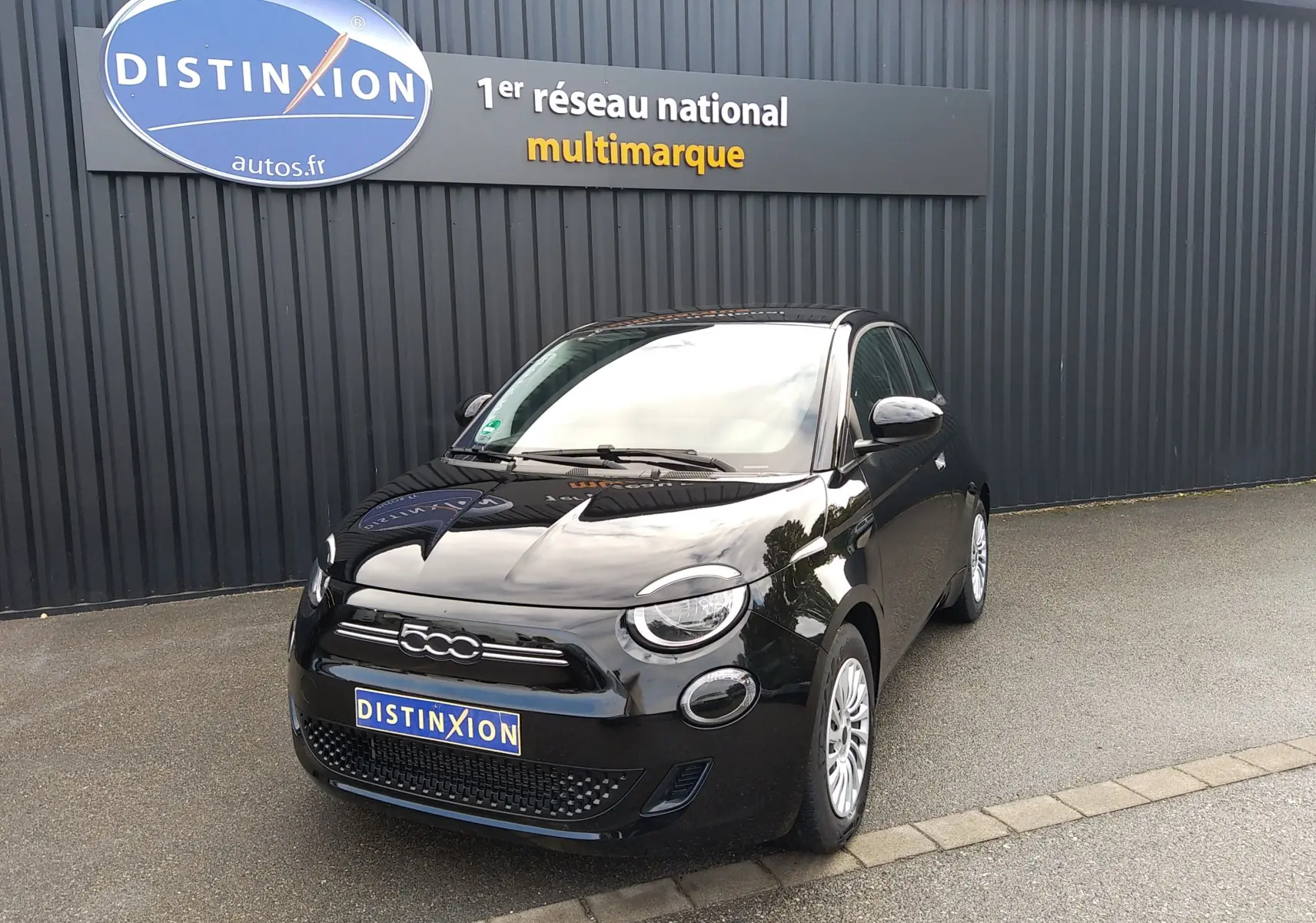 Fiat 500 électrique noire vue 3/4 avant droit, avec phares LED ronds et calandre noire brillante.