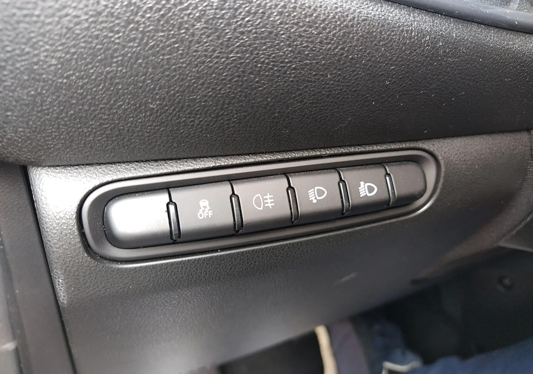 Gros plan sur les boutons de commande d’éclairage et d’aide à la conduite dans une Fiat 500 électrique noire de 2024.