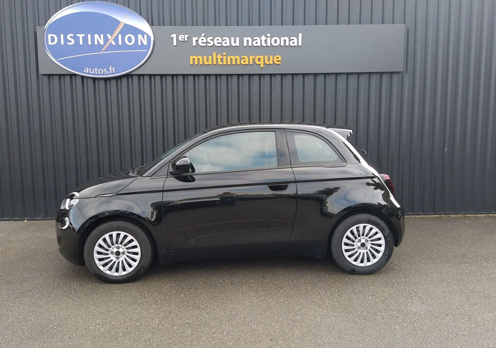 Profil côté gauche d'une FIAT 500 électrique noire 2024, compacte avec jantes argentées et vitres teintées.