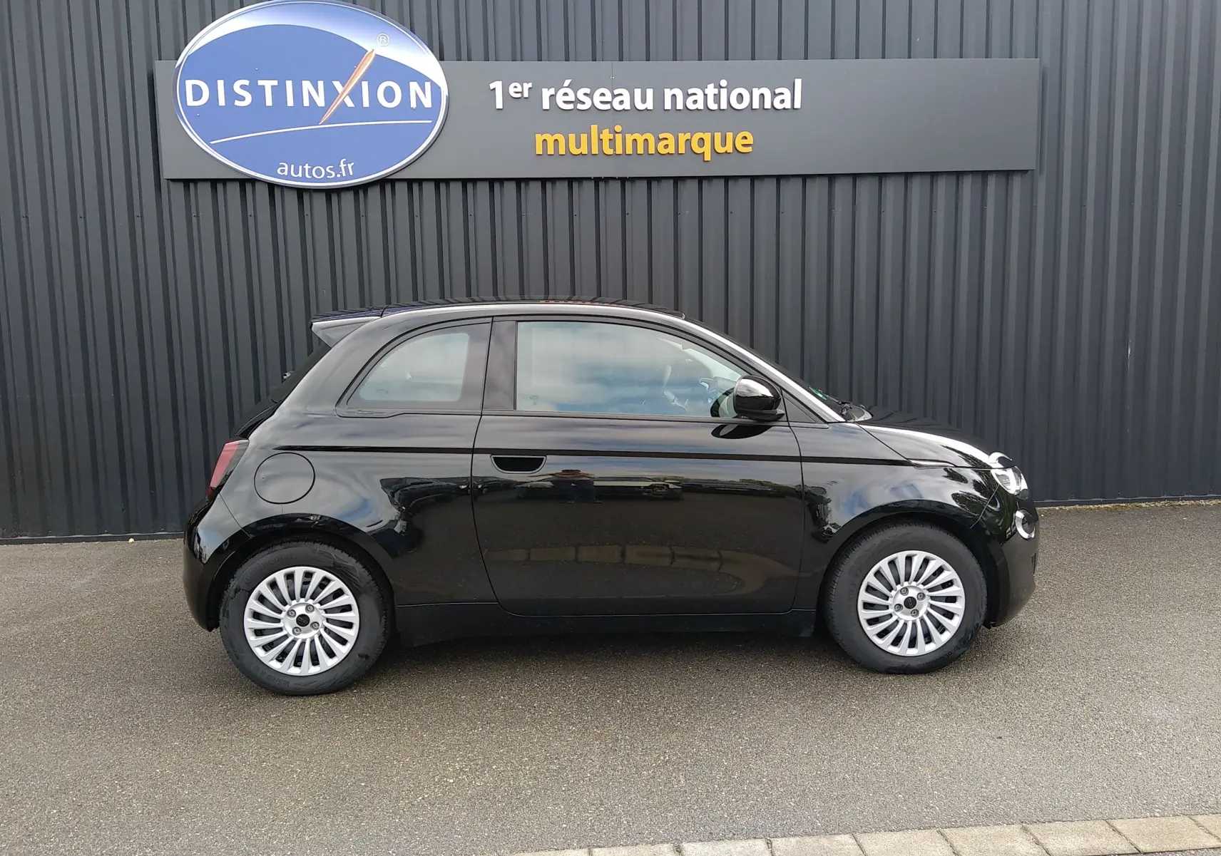Profil droit d'une Fiat 500 électrique noire 2024, compacte avec jantes argentées et toit panoramique.