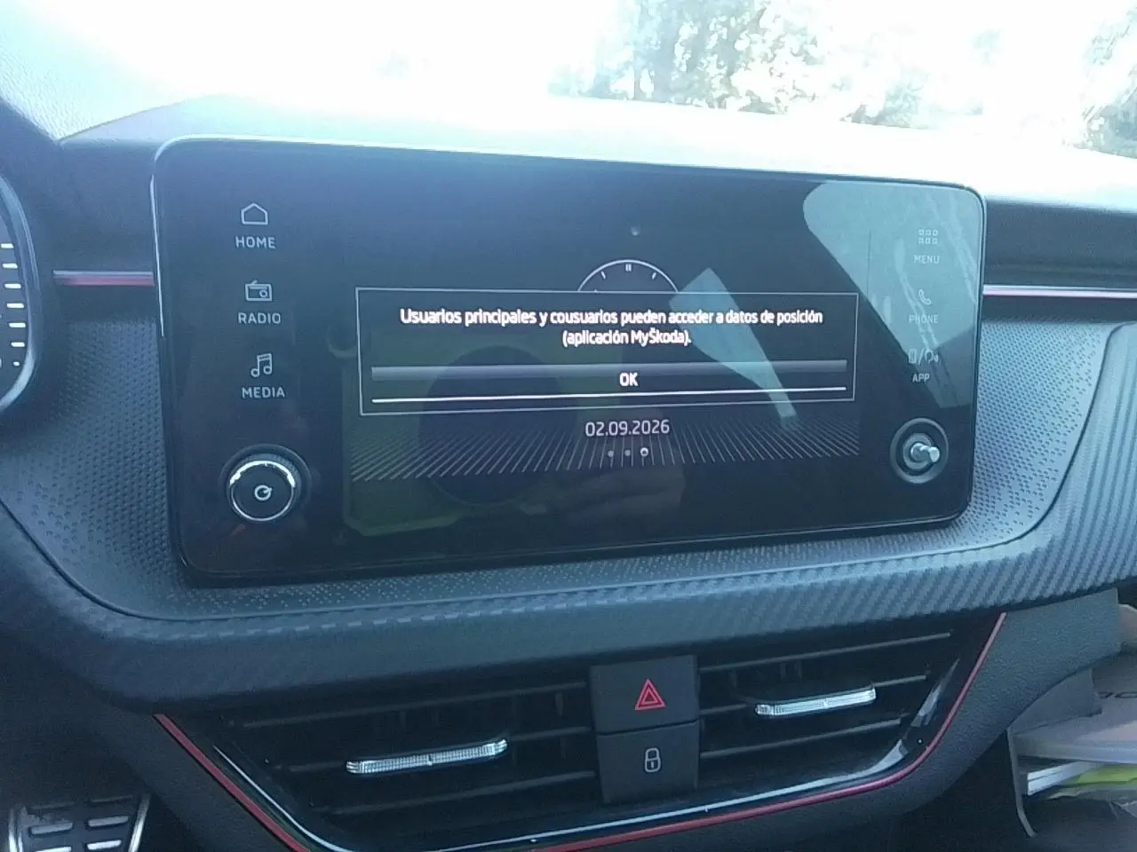 Vue rapprochée de l’écran tactile central du tableau de bord avec insert effet carbone et liseré rouge du Skoda Scala noir.