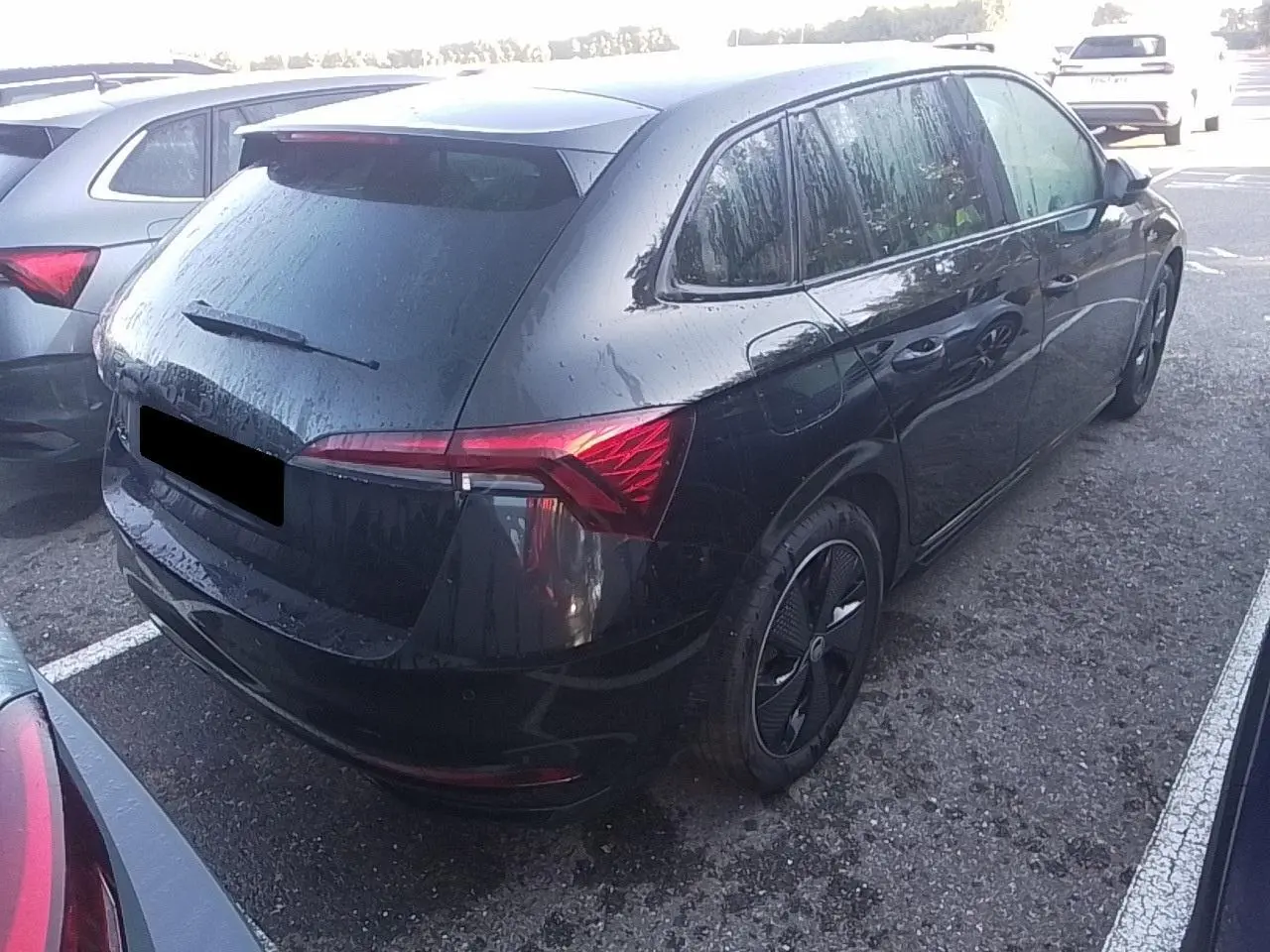 Vue 3/4 arrière droite d'une Skoda Scala TSI 116 DSG7 Monte-Carlo noire avec hayon électrique et jantes noires.