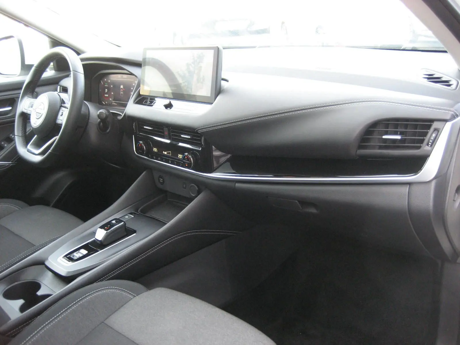 Intérieur du Nissan Qashqai III E-POWER 2024 vu côté passager, avec tableau de bord noir et écran tactile central.