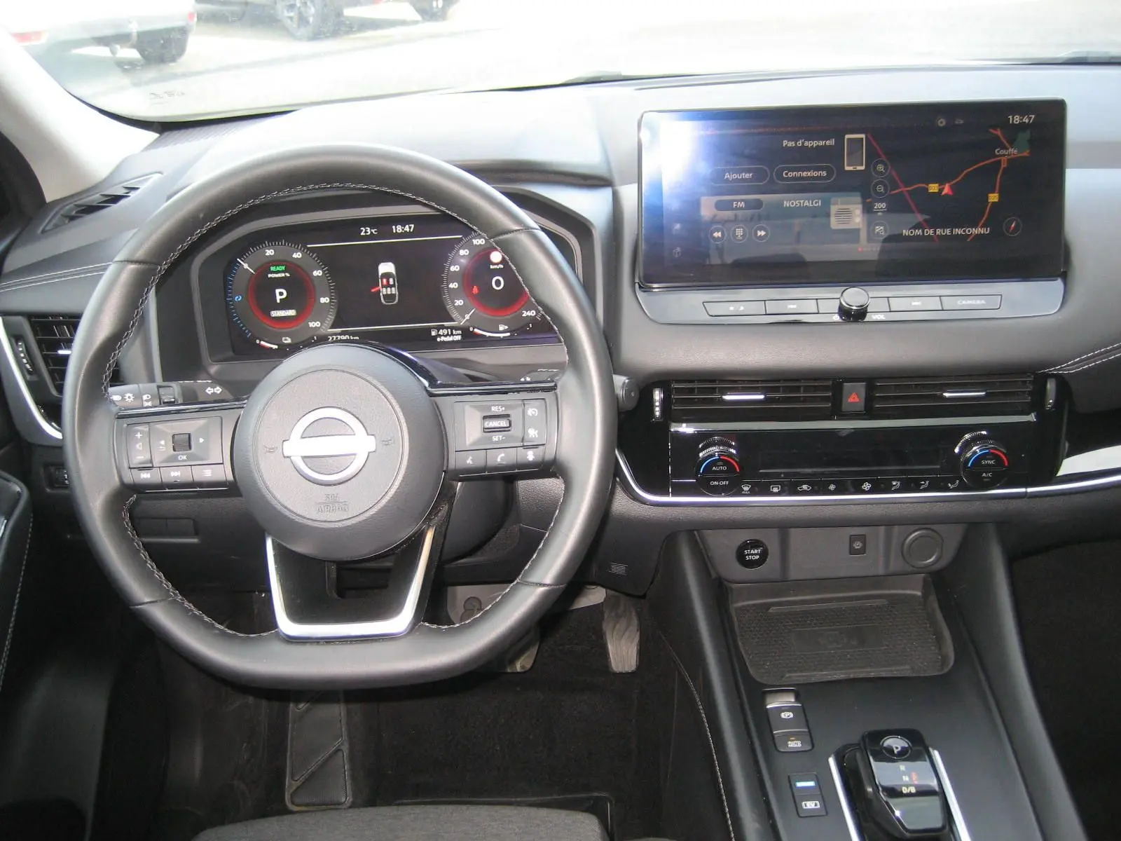 Vue intérieure du tableau de bord et volant du Nissan Qashqai blanc 2024 avec écran tactile et commandes au volant.