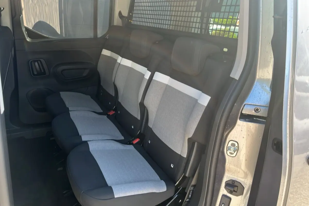 Vue intérieure côté droit du Citroën Berlingo 2025 gris artense, montrant les sièges arrière en tissu bicolore avec séparation métallique.