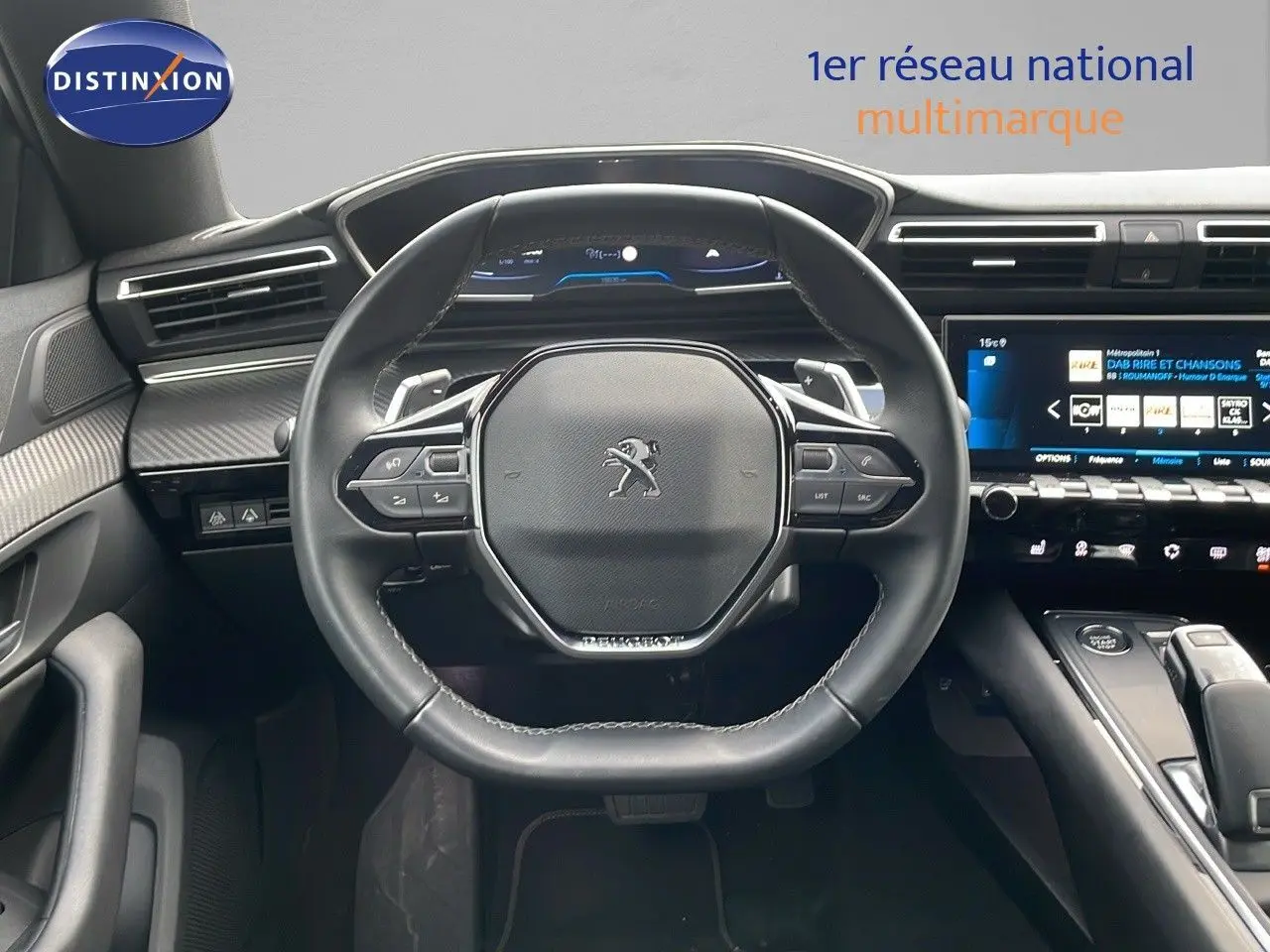 Vue intérieure centrée sur le volant cuir noir et le tableau de bord numérique de la Peugeot 508 2023.