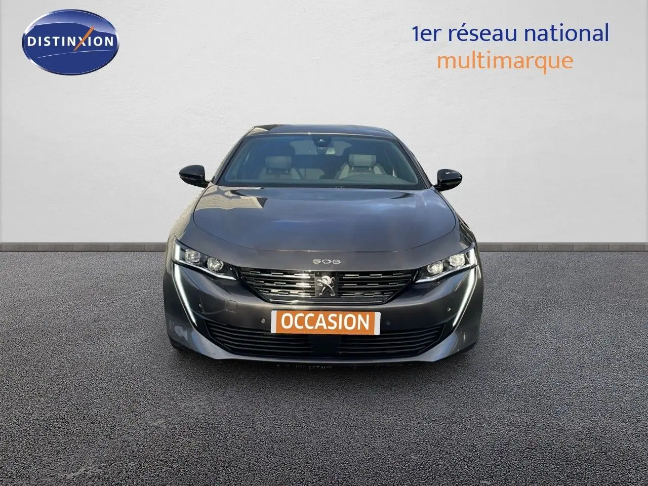 Vue frontale d'une Peugeot 508 gris platinium métal 2023 avec calandre et feux LED distinctifs, plaque "OCCASION" visible.